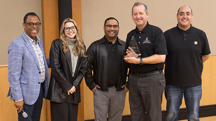 Chris Clements accepts the OneIT Excellence in Customer Service Awardee on behalf of Sheryll Del Rosario with OneIT Awards Committee members Ed Legaspi, Kevin Perez, Kirk Campbell, and Tayor Jaress.