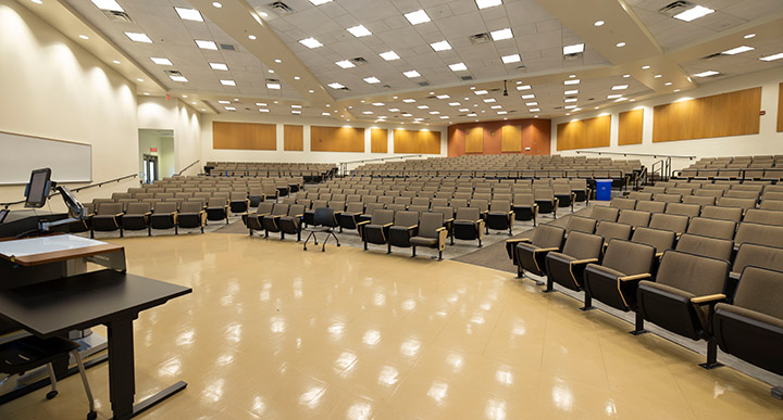 Front of classroom showing the podium, 3 sections of elevated rows of seating