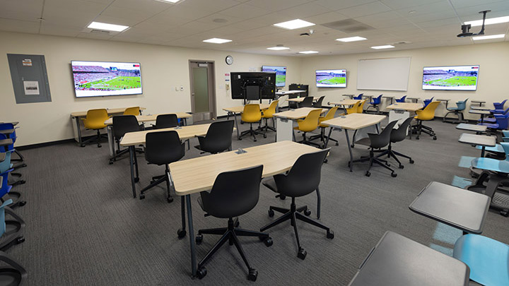 Classroom with large desks, screens on the walls