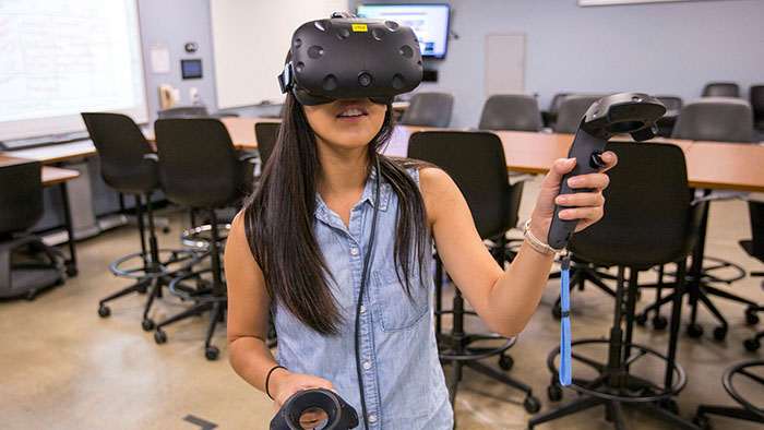 A student is pictured demonstrating a device at SDSU's new research center dedicated to expanding the use of emergent virtual technologies in the classroom.