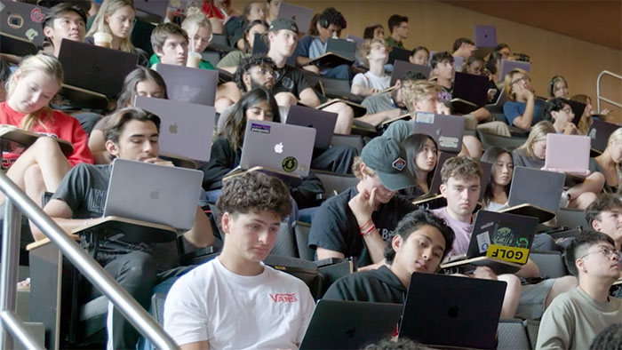 A lecture hall full of students taking notes on their laptops